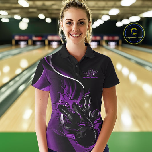 Female model front view in a bowling lane wearing a black and purple polo shirt featuring flame bowling ball striking pins in dynamic sports artwork.
