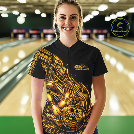 Female model wearing a black and gold bowling quarter-zip shirt at the lane with tribal flame bowling artwork.