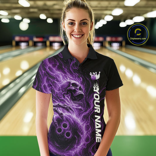 Female model wearing a black bowling polo shirt in a bowling alley featuring a skull clutching a bowling ball surrounded by swirling purple energy flames