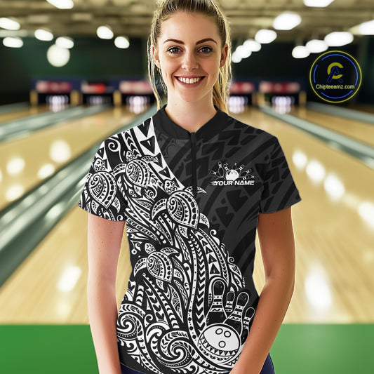 Female model wearing a black and white bowling quarter-zip shirt at the lane with tribal swirl bowling artwork.