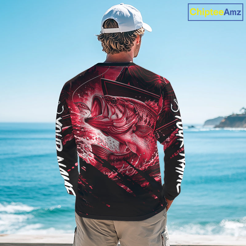 Person wearing a red and black bass fishing shirt with a fish design, standing by the ocean.