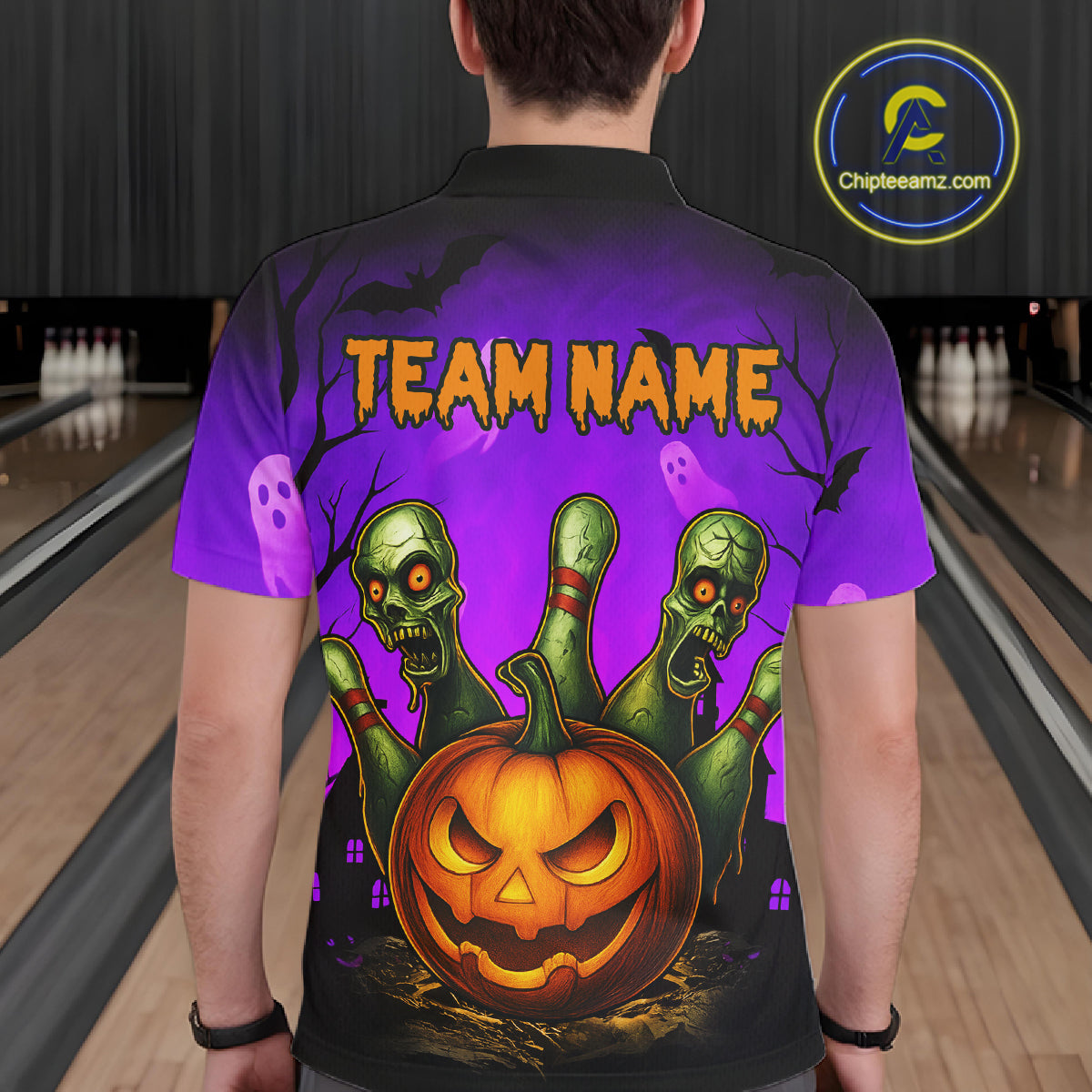 A person viewed from behind wearing a short-sleeve polo shirt with a large Halloween graphic on the back. The design shows a glowing jack-o'-lantern pumpkin, three green zombie hands, purple ghosts, bats, and the text 'TEAM NAME' in orange.