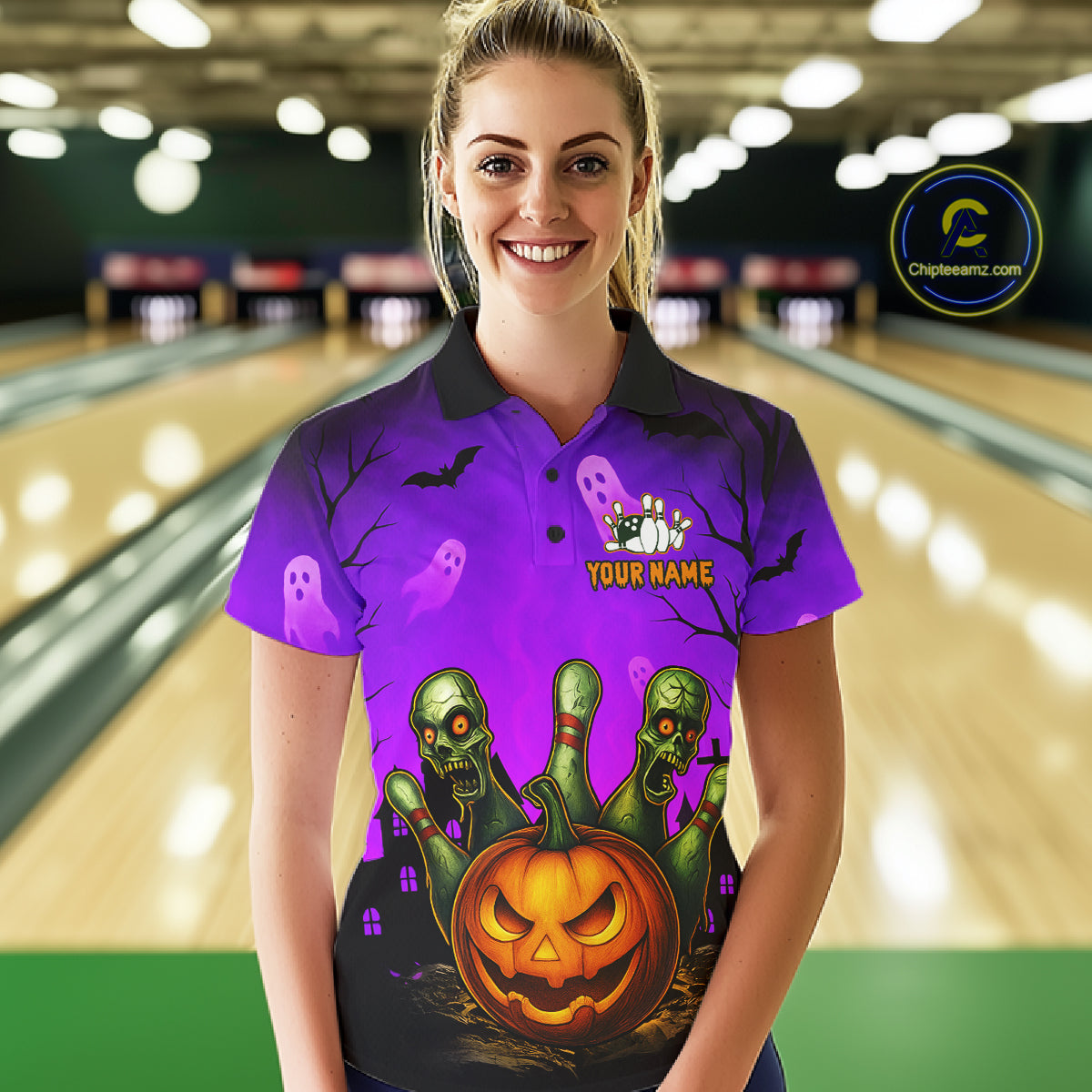 A woman wearing a purple Halloween-themed bowling shirt stands in front of a blurred bowling alley background. The shirt features a black collar, a purple background with ghost and bat motifs, and a large graphic of three green skulls emerging from a jack-o'-lantern with bowling pins.