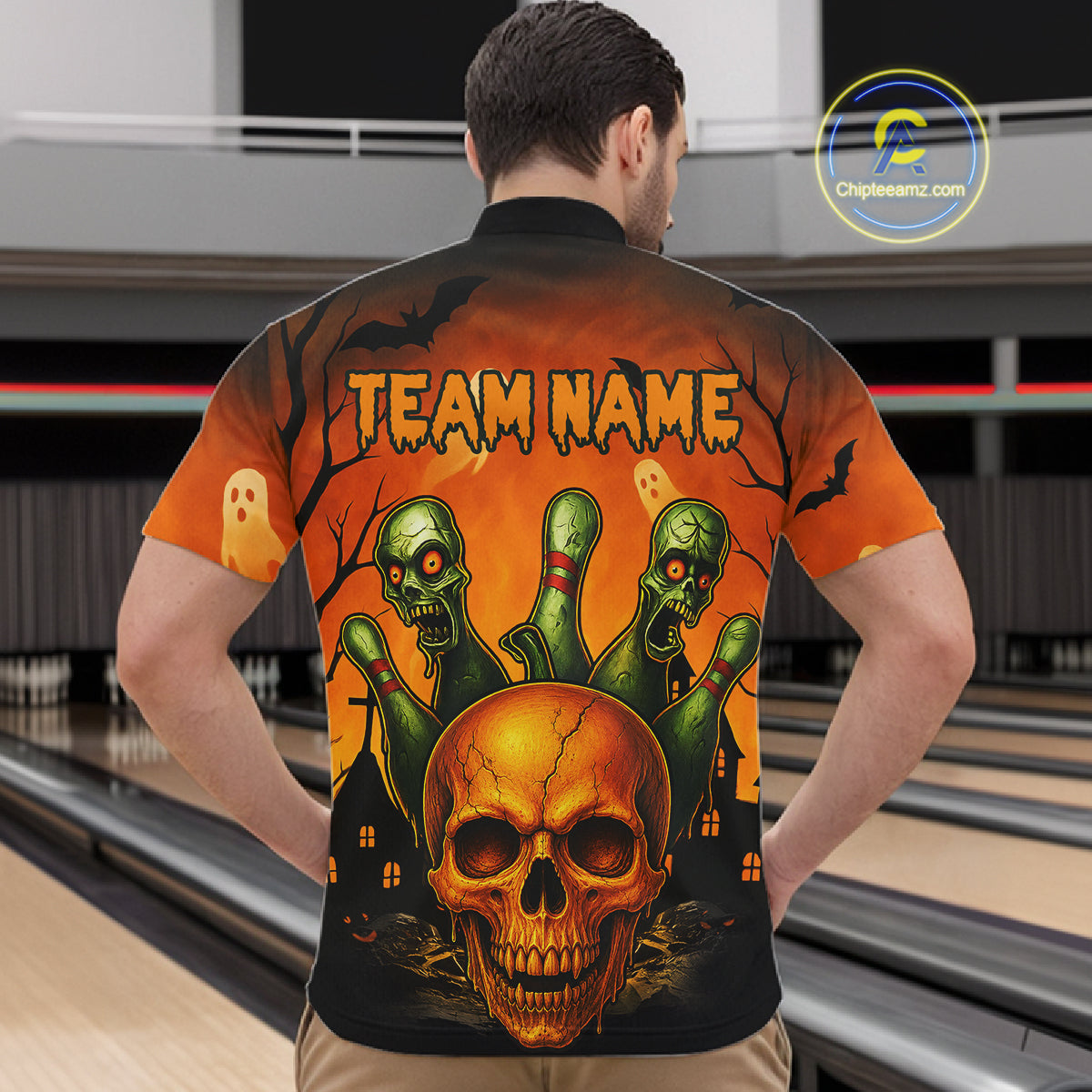 A man viewed from behind wearing a short-sleeve bowling shirt with a large Halloween graphic on the back. The design features a glowing orange skull, three green zombie hands, ghosts, bats, and the text 'TEAM NAME' on an orange-to-black gradient background.