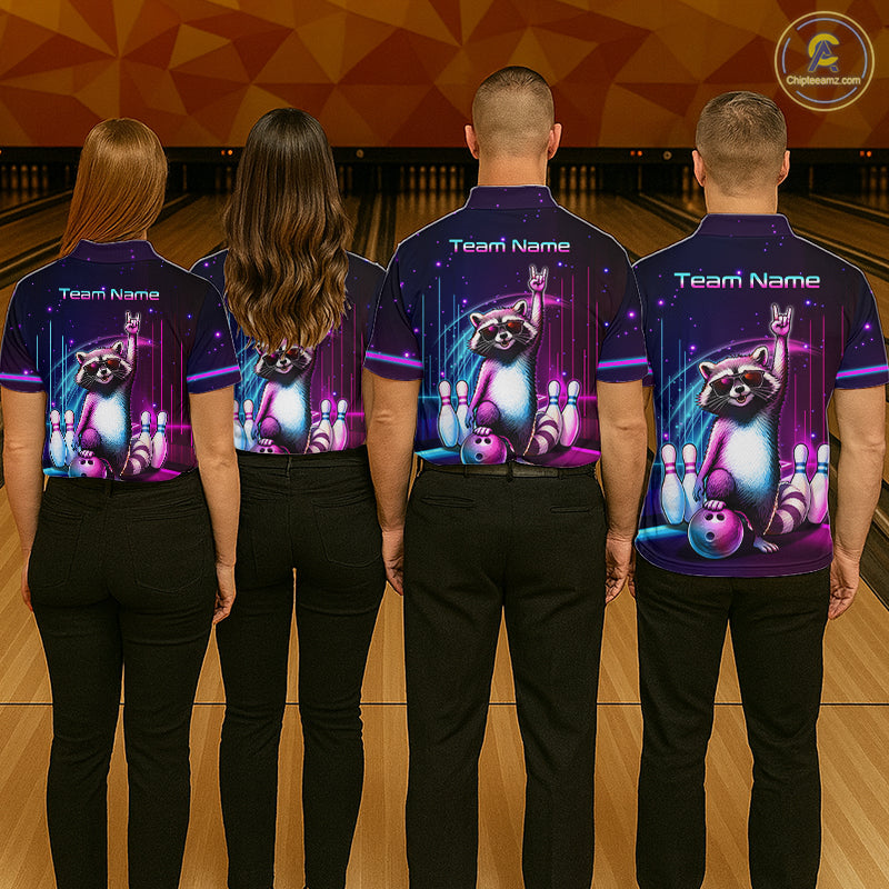 Four people standing with their backs to the camera in a bowling alley, wearing matching dark purple short-sleeve bowling shirts with a raccoon and bowling pins graphic on the back, paired with black pants.