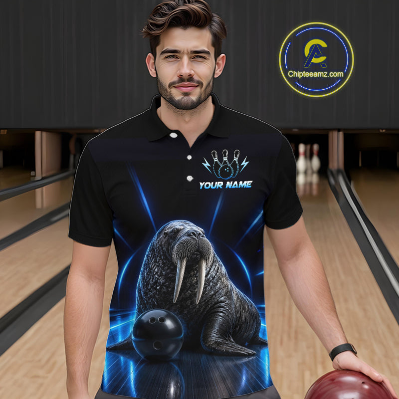 Man wearing a black polo shirt with a walrus and bowling ball design in a bowling alley.