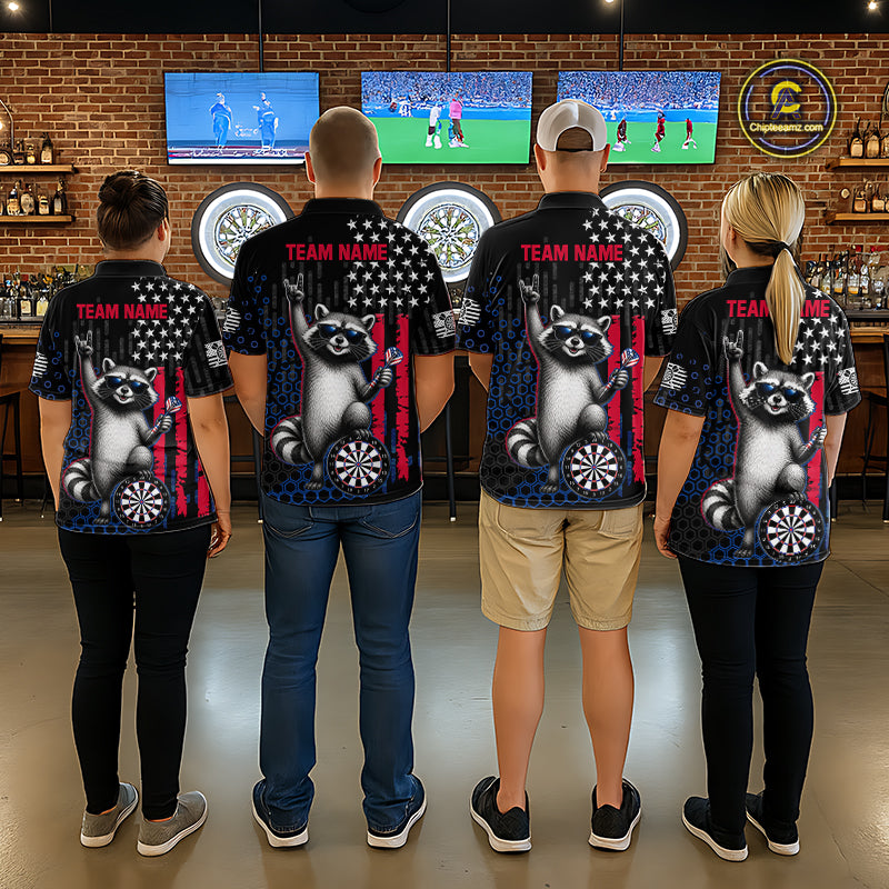 Four people standing with their backs to the camera in a bar, wearing matching black short-sleeve shirts with a large raccoon graphic, American flag motif, and dartboard print. The shirts also feature 'TEAM NAME' text on the upper back.