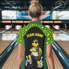 Load image into Gallery viewer, A person viewed from behind wearing a short-sleeve bowling shirt in a bowling alley. The shirt has a green and black turtle-scale pattern, yellow 'TEAM NAME' text, and a cartoon turtle graphic on the back.