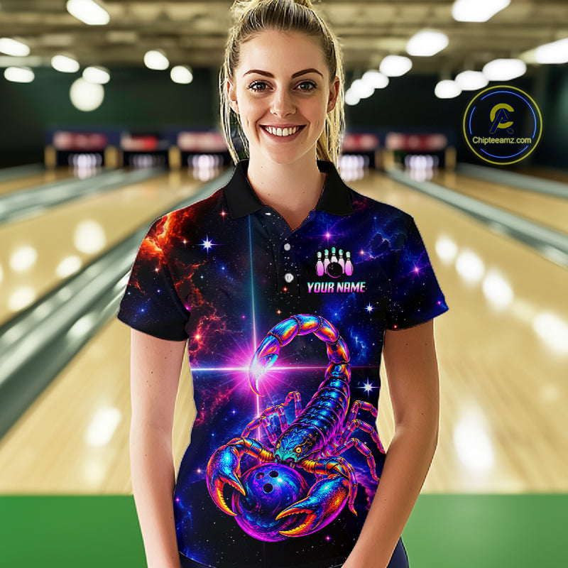 A woman stands in a bowling alley wearing a short-sleeve polo shirt with a vivid cosmic scorpion graphic on a dark space background. The shirt has a black collar and sleeve trim, a button placket, and a customizable chest area with bowling pins and the text 'YOUR NAME'.