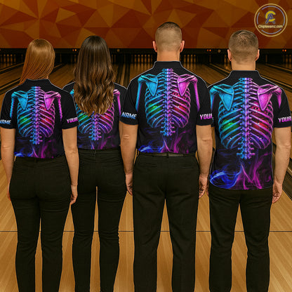 Four people standing in a bowling alley, viewed from behind, wearing matching black short-sleeve shirts with a vivid neon skeleton back print in blue, purple, pink, and green. The shirts have placeholder text on the back and the left sleeve, and the people are wearing black pants.