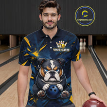 Load image into Gallery viewer, Male model wearing a custom blue bulldog bowling polo shirt front view featuring a fierce cartoon bulldog, bowling ball, gold lightning accents and navy blue abstract pattern at the bowling alley