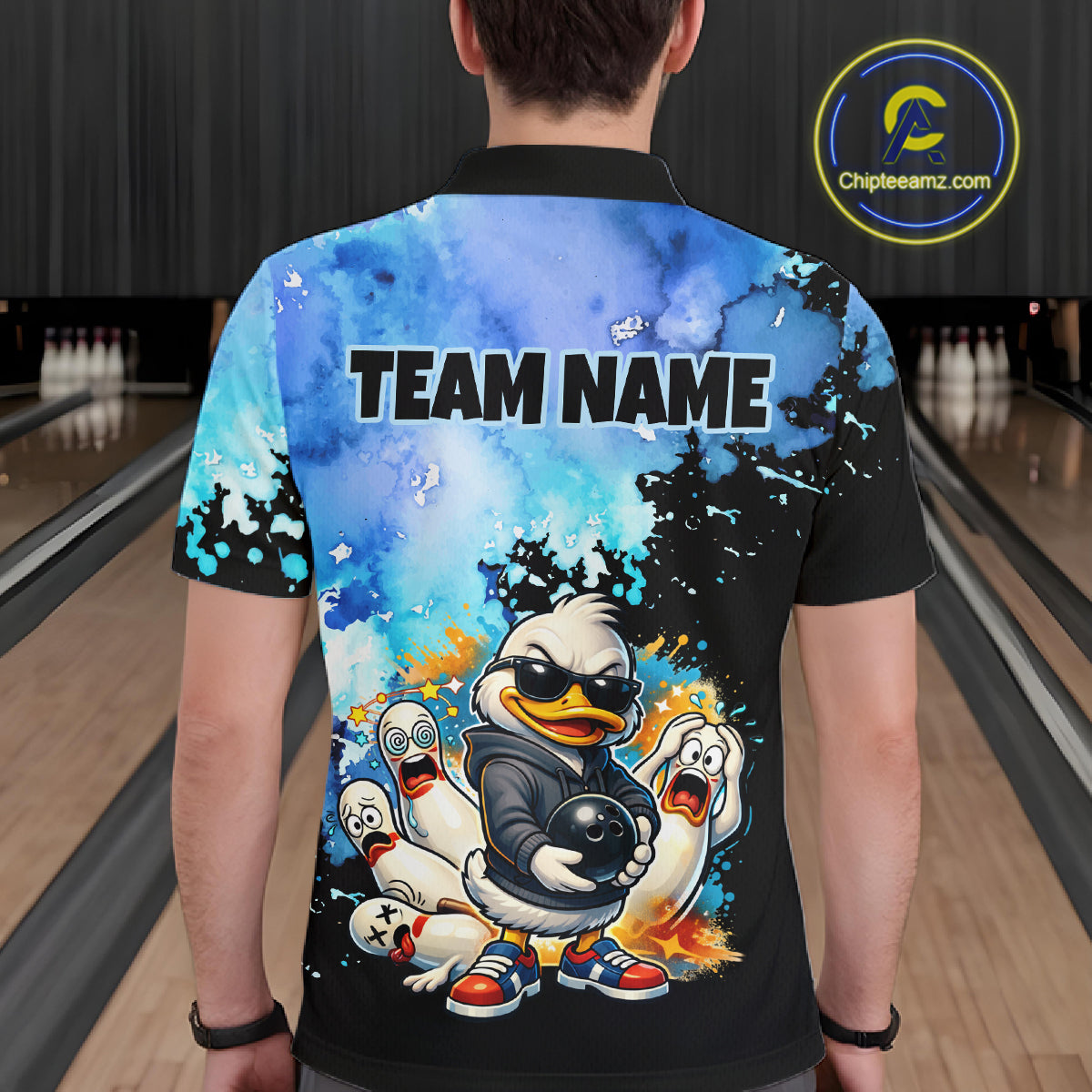 Person wearing a colorful bowling shirt with cartoon characters and 'TEAM NAME' text in a bowling alley.