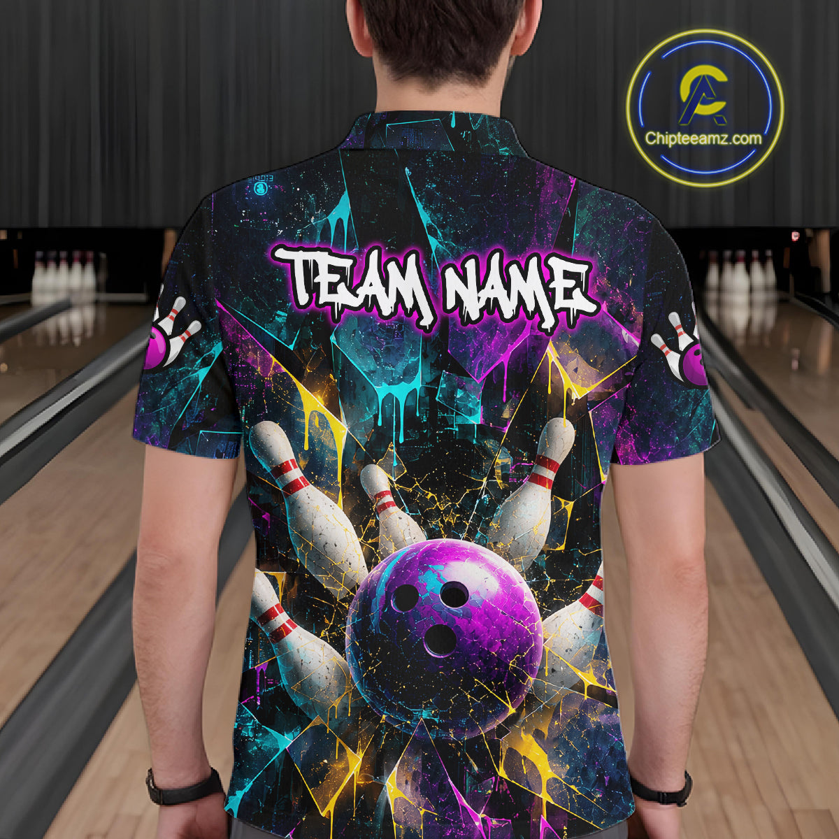 A man viewed from behind wearing a short-sleeve bowling-themed t-shirt with a vibrant cosmic design. The shirt features a purple and blue bowling ball, bowling pins, and the text 'TEAM NAME' on the back.