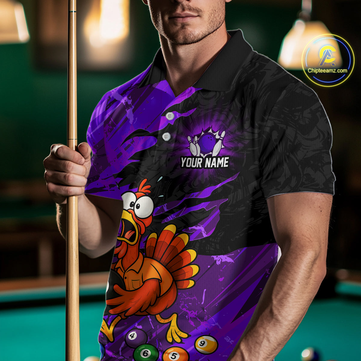 A man wearing a custom purple and black polo shirt with a cartoon turkey graphic and pool balls, holding a pool cue in a dimly lit pool room. 