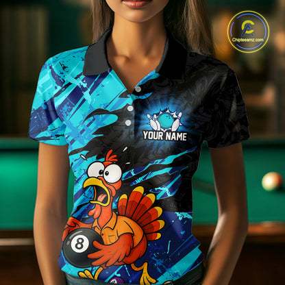 A woman wearing a short-sleeve polo shirt with a vibrant blue and black graphic design featuring a cartoon turkey holding an 8-ball and the text 'YOUR NAME'. The background shows a blurred pool table.