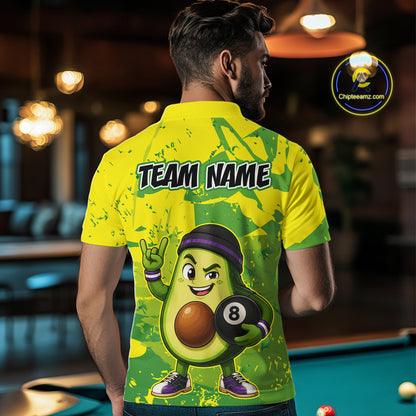 Person wearing a yellow and green shirt with an avocado character holding a pool ball, standing in a bar.