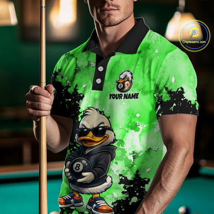 A man wearing a bright green and black custom-printed polo shirt with a cartoon duck character holding an 8-ball, holding a pool cue in a dimly lit pool hall. 
