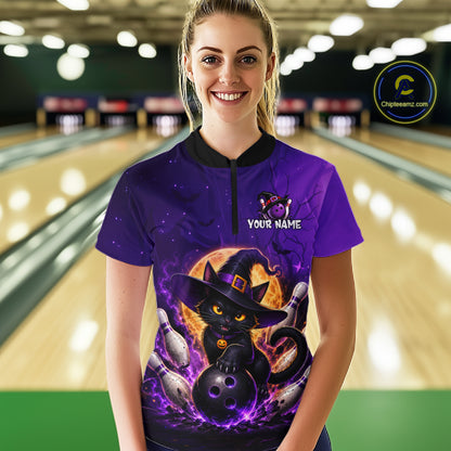 A woman stands in a bowling alley wearing a purple short-sleeve bowling shirt with a black collar and a large Halloween graphic of a black cat in a witch hat holding bowling balls. The shirt has a mock neck and a customizable name print on the chest.