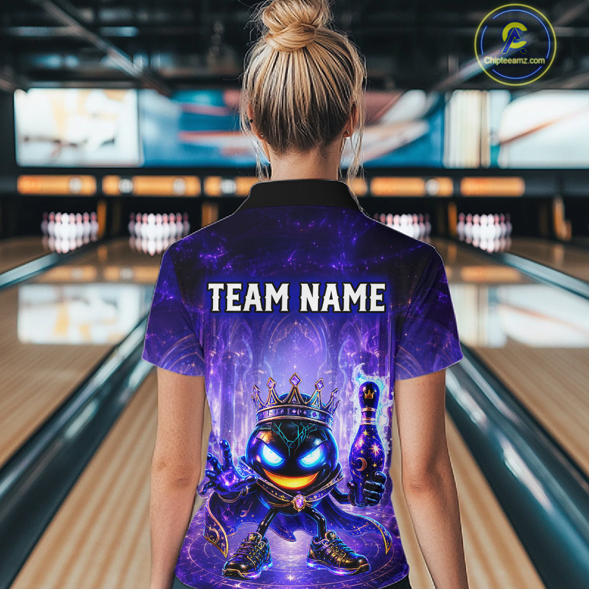 Person wearing a purple bowling shirt with a team name design in a bowling alley.