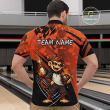 Load image into Gallery viewer, A man viewed from behind wearing a short-sleeve bowling shirt with a bold orange and black graphic design featuring a cartoon monkey and the text 'TEAM NAME' on the back. Bowling lanes are visible in the background, and a 'Chipteamz.