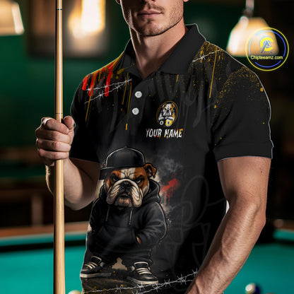 A man wearing a black custom polo shirt with a graphic of an English Bulldog in a hoodie and cap, holding a pool cue in a dimly lit pool hall. The shirt features a bulldog graphic, a custom name placeholder, and paint splatter details.