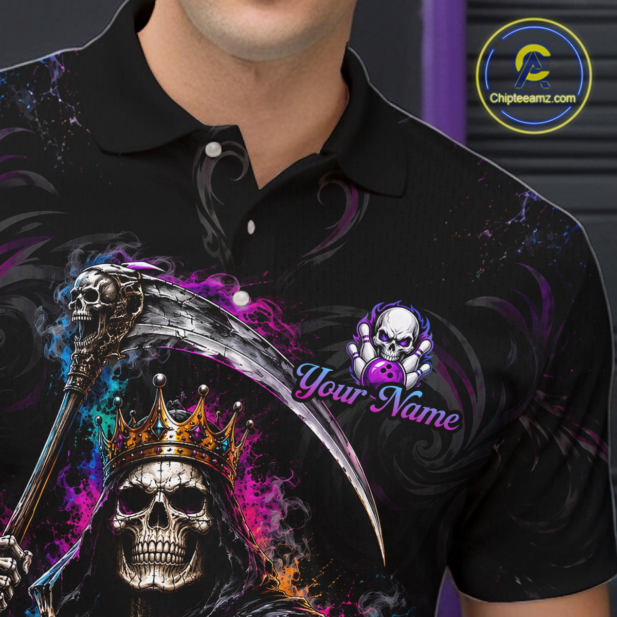 A close-up of a person wearing a black polo shirt with a large graphic print featuring a grim reaper skull with a gold crown, a scythe, purple and blue smoke effects, and a customizable skull logo with the text 'Your Name'. 