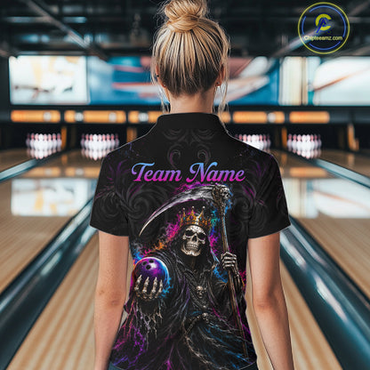 A woman viewed from behind wearing a black short-sleeve polo shirt with a large grim reaper graphic and the words 'Team Name' on the back, standing in a bowling alley.