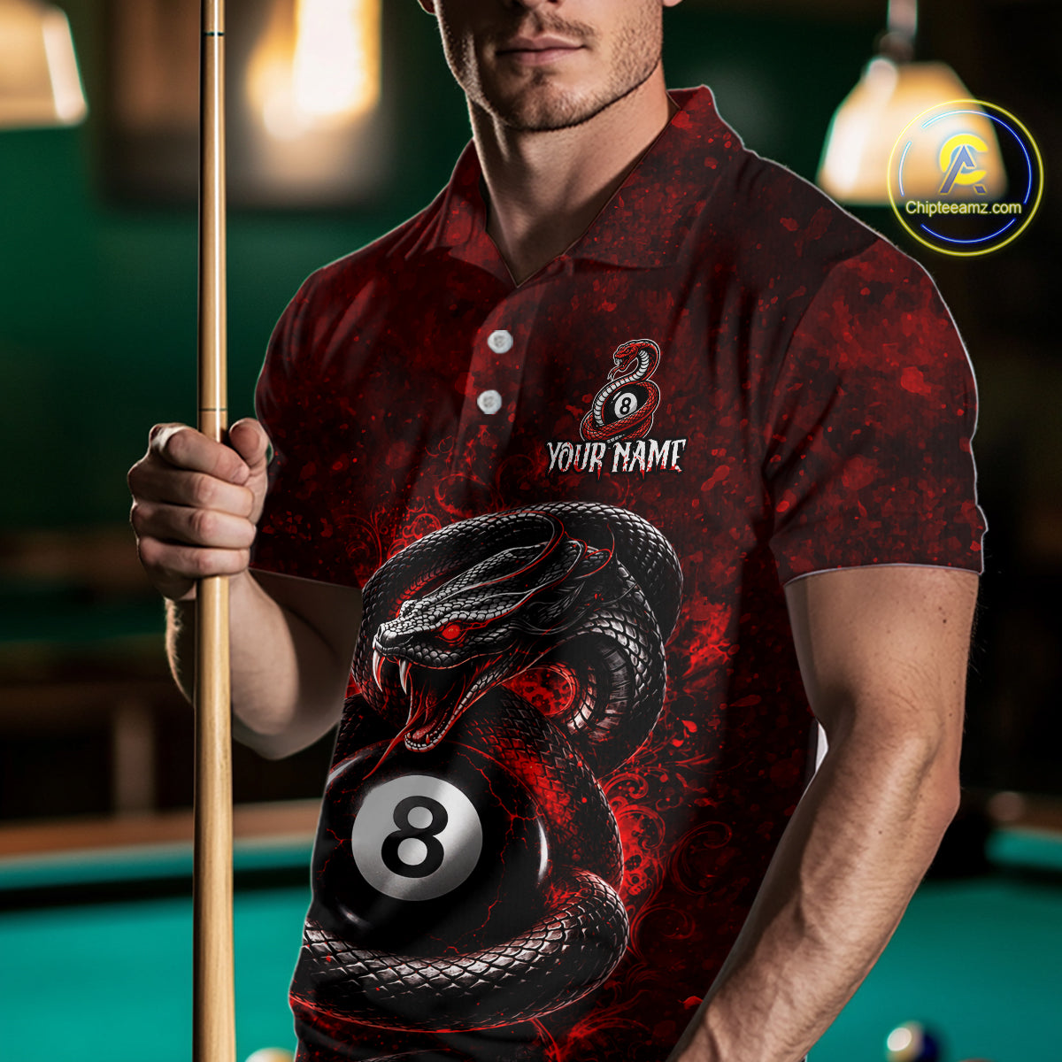A man in a pool hall wearing a red and black polo shirt with a graphic of a coiled snake wrapping around an 8-ball, holding a pool cue. The shirt features a customizable design with the text 'YOUR NAME' and a logo.