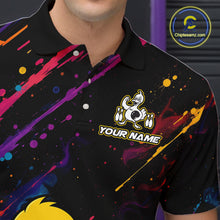 Load image into Gallery viewer, A close-up of a person wearing a black short-sleeve polo shirt with colorful paint-splatter graphics in purple, pink, blue, yellow, and orange. The shirt features a cartoon duck logo with the text 'YOUR NAME' on the chest.