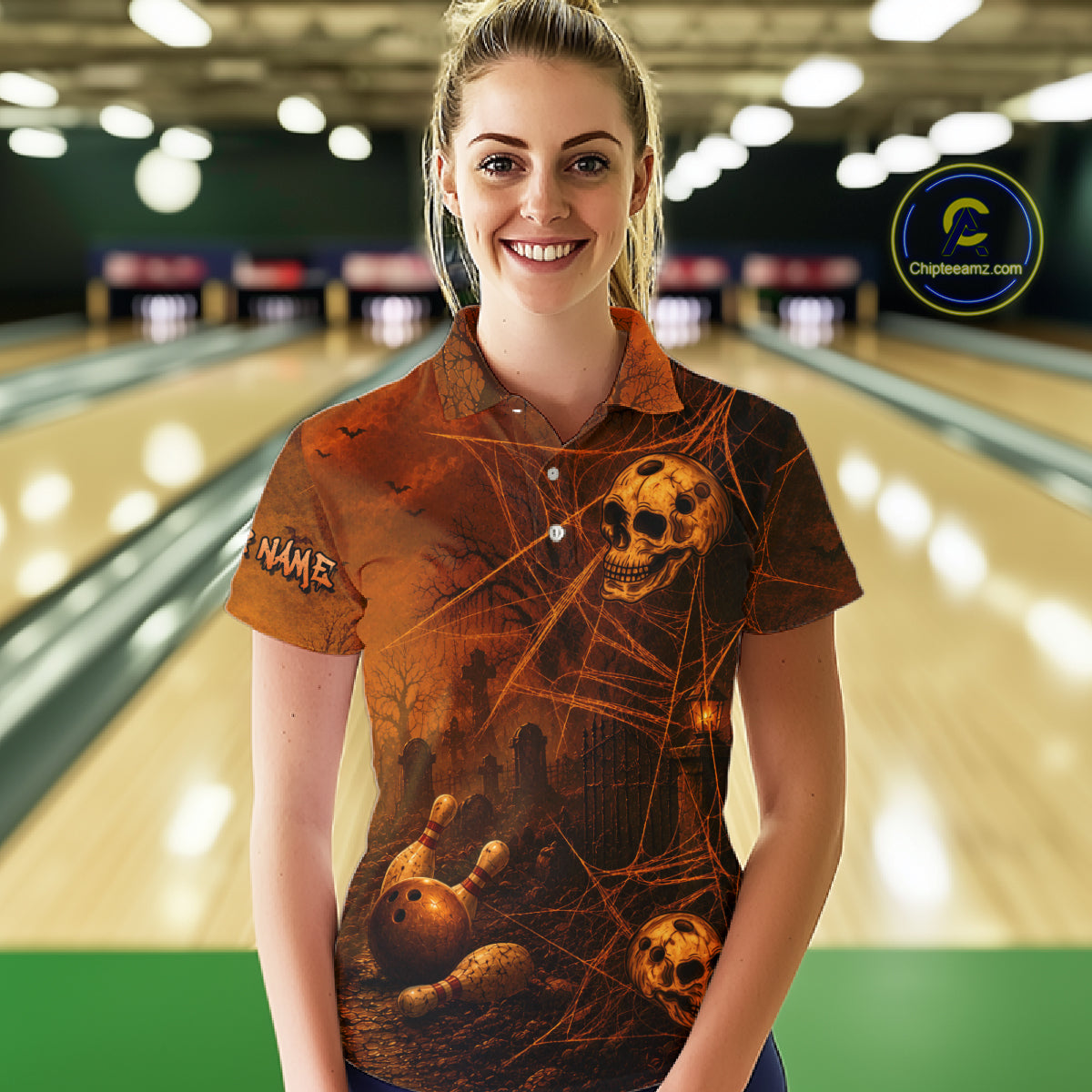 A woman wearing a short-sleeve polo shirt with a Halloween-themed graphic print featuring skulls, bowling balls, and cobwebs, standing in front of a blurred bowling alley background. 