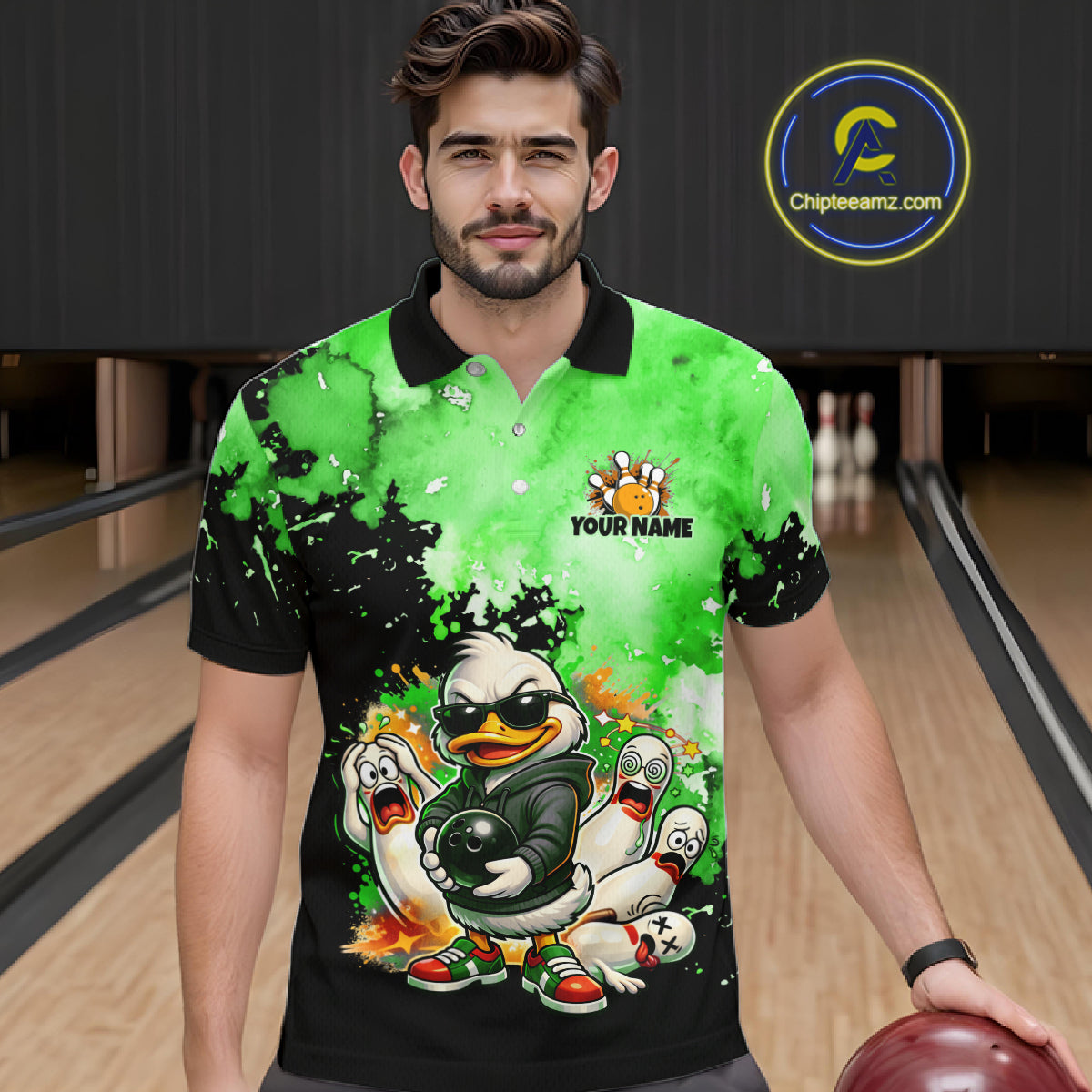 A man wearing a custom bowling-themed short-sleeve polo shirt with a green and black splatter design, cartoon ducks, and a 'YOUR NAME' placeholder logo on the chest. The background shows bowling lanes