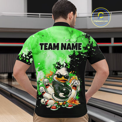 A man viewed from behind wearing a custom bowling shirt with a bright green and black watercolor design, featuring a cartoon duck mascot and the text 'TEAM NAME' on the back. The background shows bowling lanes in a bowling alley.
