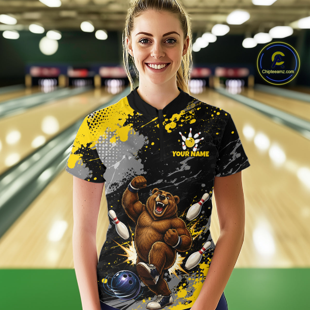 A woman stands in a bowling alley wearing a custom black, yellow, and gray short-sleeve bowling t-shirt with a cartoon bear graphic and 'YOUR NAME' text. 