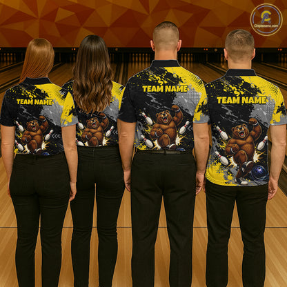 Four people standing with their backs to the camera in a bowling alley, wearing matching bowling shirts with a custom brown bear graphic and 'TEAM NAME' printed on the back.