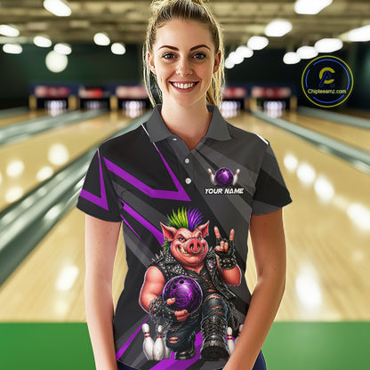 A woman stands in a bowling alley wearing a dark gray short-sleeve polo shirt with a custom graphic of a pig bowling character holding a purple bowling ball. The shirt features purple and gray geometric patterns and a placeholder chest print reading 'YOUR NAME'.
