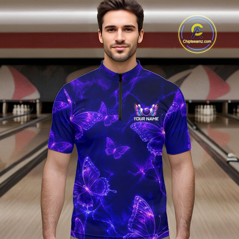 A man wearing a short-sleeve quarter-zip athletic shirt with a purple and blue neon butterfly pattern, standing in a bowling alley. The shirt features a black zipper at the collar and a customizable chest graphic that reads 'YOUR NAME' with bowling pins behind it.
