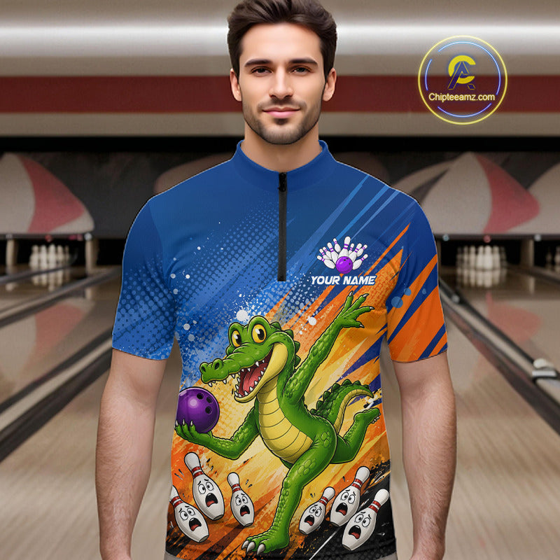 A man wearing a short-sleeve bowling quarter-zip jersey with a cartoon alligator holding a purple bowling ball, set against a blurred bowling alley background. The jersey features blue, orange, and yellow graphics with the text 'YOUR NAME' 