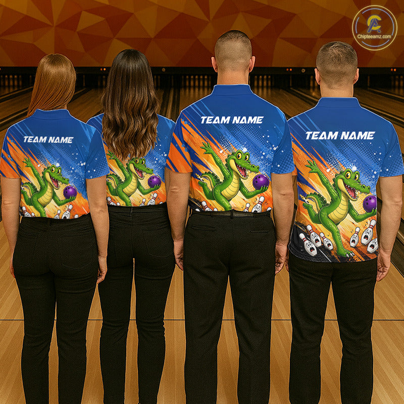 Four people standing in a bowling alley, shown from the back, wearing matching blue bowling shirts with a colorful green alligator graphic and black pants. The shirts have 'TEAM NAME' printed on the upper back.