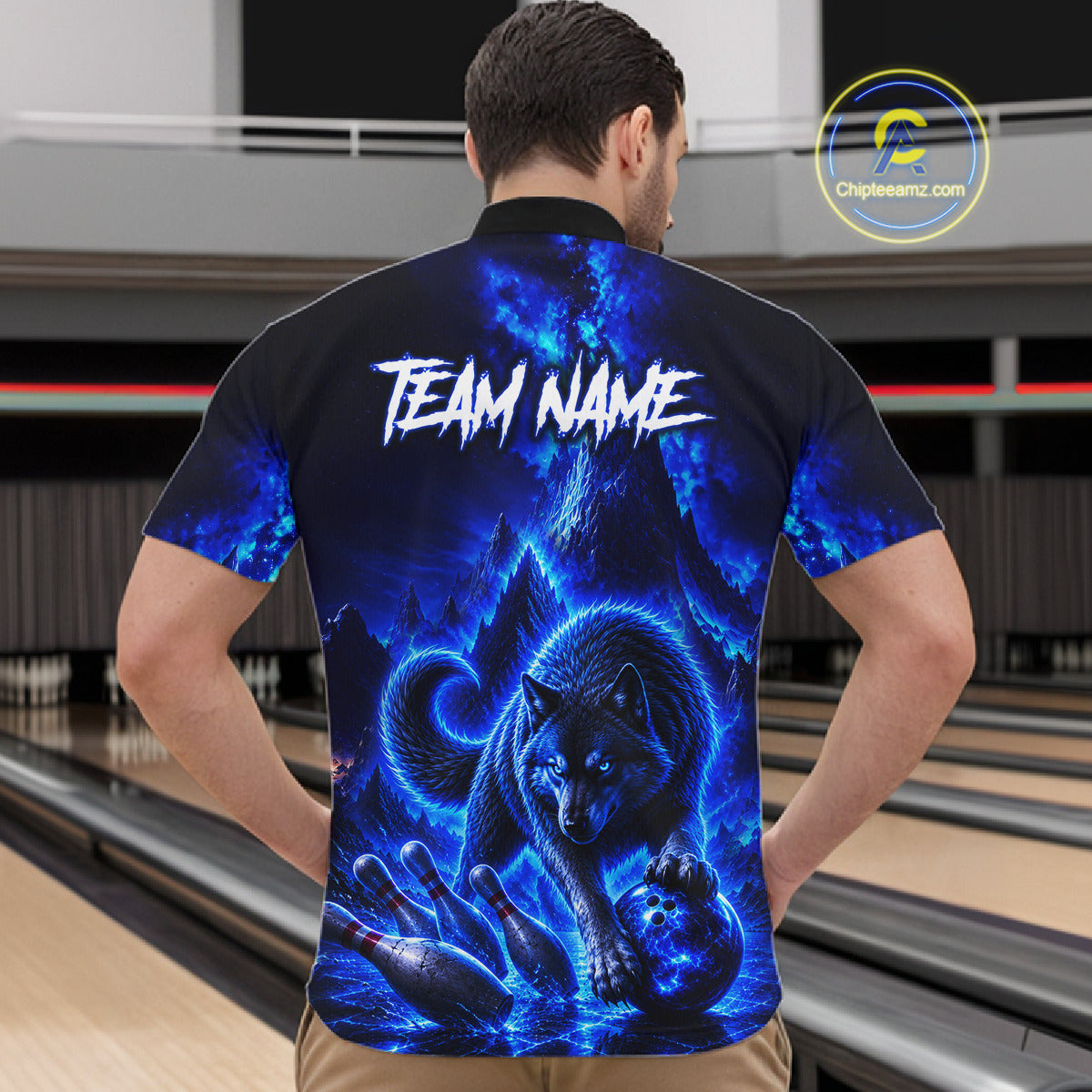 Person wearing a black t-shirt with a blue wolf design and 'TEAM NAME' text on the back, standing in a bowling alley.