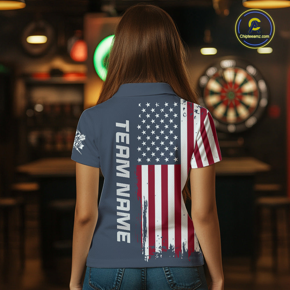A woman viewed from behind wearing a short-sleeve polo shirt with a distressed American flag print on the back and the words 'TEAM NAME' printed vertically. The shirt is navy blue with red, white, and blue graphics.