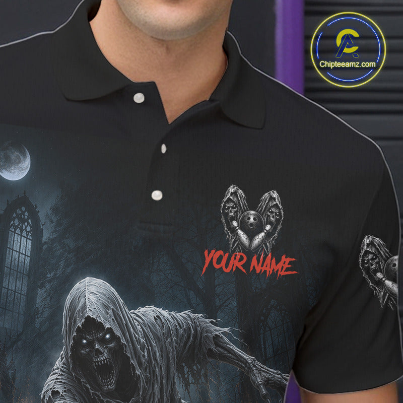 A close-up of a person wearing a black short-sleeve polo shirt with a dark gothic horror graphic print featuring a hooded skull figure, a winged skull heart, and red placeholder text reading 'YOUR NAME'. 