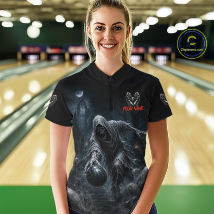 A woman wearing a black bowling shirt with a dark gothic grim reaper graphic and 'YOUR NAME' text, standing in a bowling alley with lanes blurred in the background.
