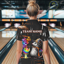 Load image into Gallery viewer, A woman viewed from behind wearing a black short-sleeve bowling-themed graphic shirt in a bowling alley. The shirt features a large printed design with the text 'TEAM NAME', a raccoon in a hat, a bowling ball, and colorful splatter details.