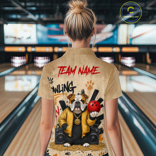 Load image into Gallery viewer, A woman viewed from behind wearing a tan short-sleeve bowling shirt with a large graphic print of a bulldog holding a red bowling ball and the words 'TEAM NAME' and 'BOWLING'. The background shows a blurred bowling alley with lanes and pins.