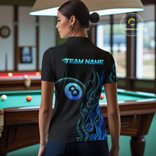 Load image into Gallery viewer, Women wearing billiards polo shirt featuring an eight ball design surrounded by flowing blue flame graphics on a black background.