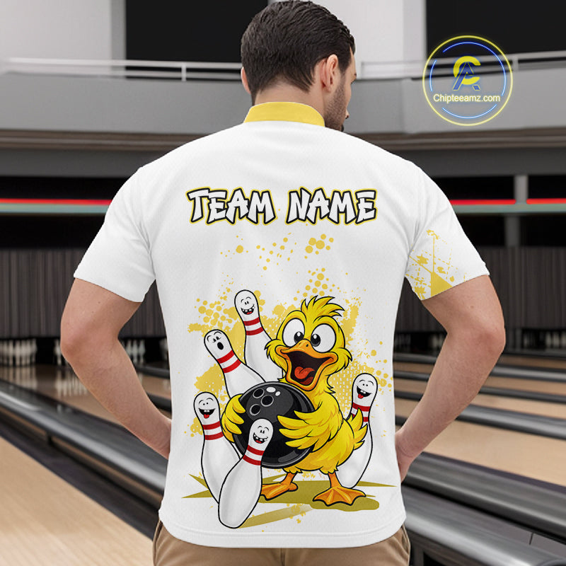 A man viewed from behind wearing a white bowling-themed t-shirt with a cartoon yellow duck holding bowling pins and the text 'TEAM NAME' printed on the back. The background shows a blurred bowling alley.