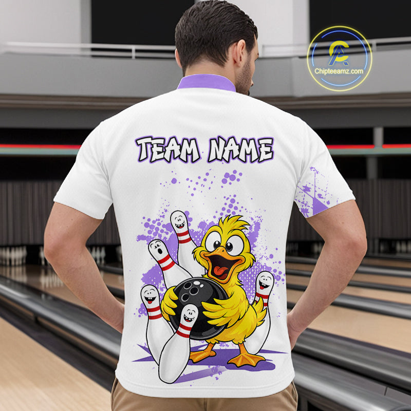 A man viewed from behind wearing a white bowling-themed t-shirt with a cartoon yellow duck holding bowling balls and pins, with 'TEAM NAME' printed on the back. The background shows a blurred bowling alley.