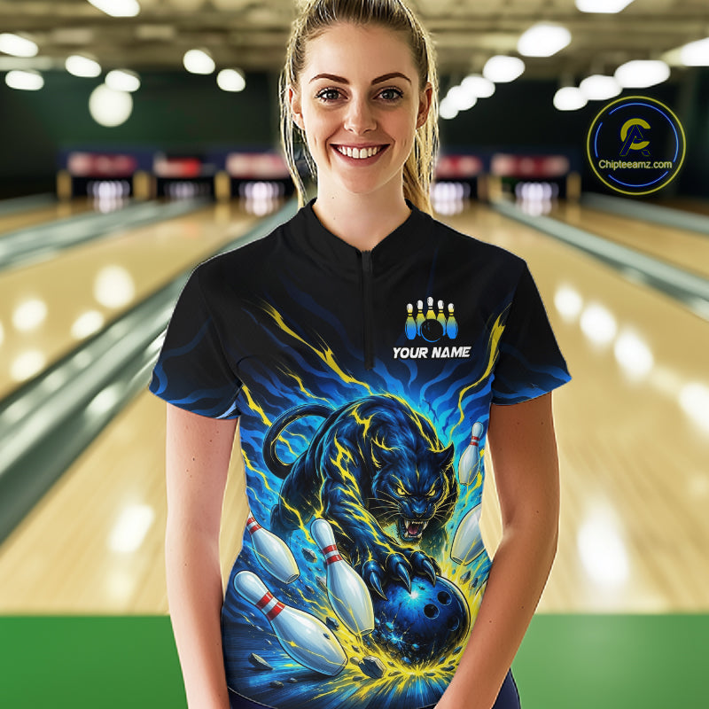 Person wearing a black bowling shirt with a colorful tiger design in a bowling alley.