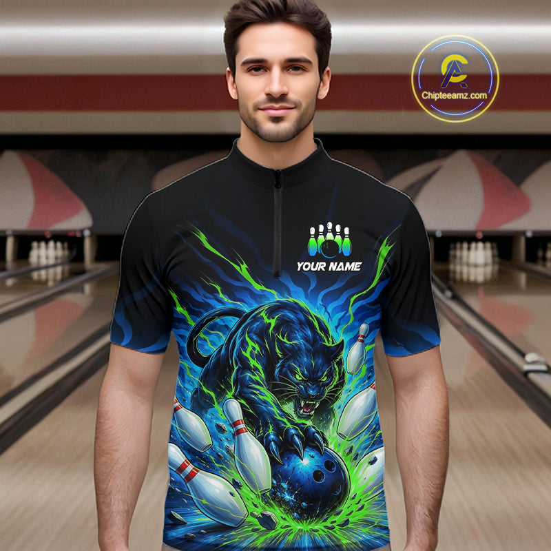 Man wearing a black bowling shirt with a green and blue panther design in a bowling alley.