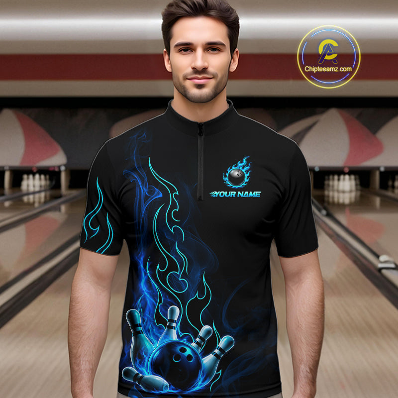 A man wearing a black short-sleeve quarter-zip bowling-themed t-shirt with blue flame graphics and a bowling ball graphic on the chest, set against a bowling alley background.